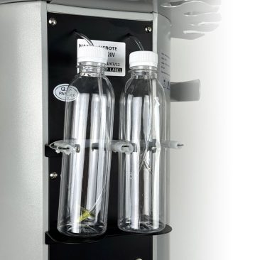 Dwie przezroczyste plastikowe butelki z białymi nakrętkami są zamocowane w metalowym uchwycie na urządzeniu do hydradermabrazji Air Essence™ Hydra Facial Therapy ESSENTIAL.