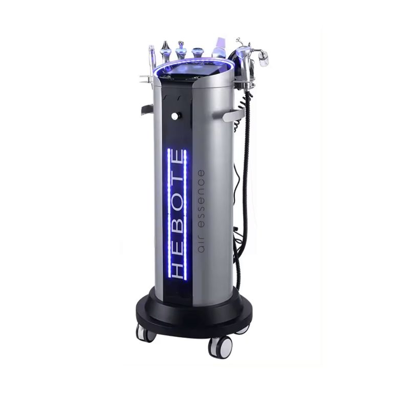 Eleganckie, cylindryczne urządzenie do hydradermabrazji 6w1 Air Essence™ Hydra Facial Therapy ESSENTIAL na czterech kółkach, wyposażone w wiele ręcznych przystawek i niebieskie akcenty LED z przodu i na górze.