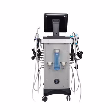 Widok z przodu urządzenia Air Essence™ Hydra Facial Therapy, kombajn kosmetyczny, z monitorem na górze, kilkoma końcówkami, przewodami, rurkami, przezroczystym niebieskim pojemnikiem pośrodku, wszystko zamontowane na czterech kółkach.