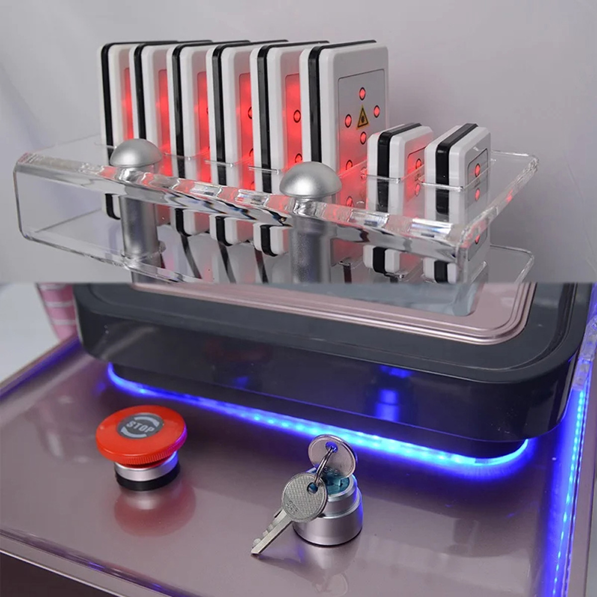 WindScrub 40K Kawitacyjne urządzenie wyszczuplające 6 w 1, Rose1 prostokątne panele z czerwonymi światłami na przezroczystej podstawie, a także czerwony przycisk zatrzymania awaryjnego i przyciski pod niebieskim podświetleniem LED.