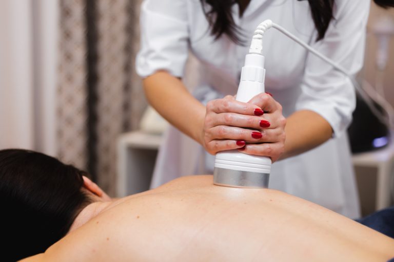 The girl in the spa salon receives a back and neck massage, lies in the cosmetology table, relaxed and enjoys the process