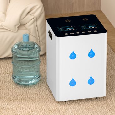 Inhalator wodoru Air Essence™ Euria E10 (1500-12000 ml, H2 + O2 gaz Browna) z niebieskimi symbolami kropli wody znajduje się na podłodze wyłożonej dywanem obok dużego dzbanka z wodą, w pobliżu beżowej kanapy i drewnianej ściany.