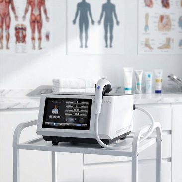 Air Essence Vortex V17 profesjonalne urządzenie do terapii falą uderzeniową stosowane w gabinecie fizjoterapii, ustawione na stoliku zabiegowym z widocznym ekranem dotykowym i podłączoną głowicą